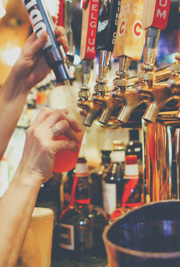 A hand pouring a beer from a selection of tap pulls